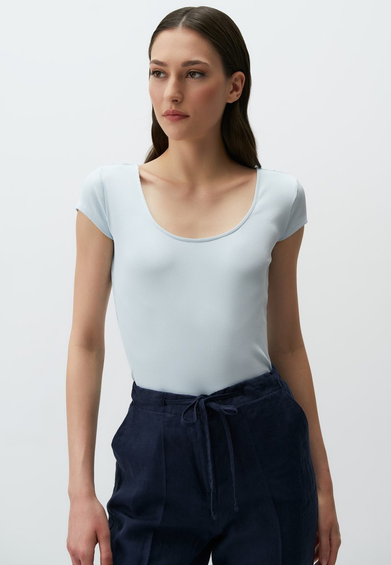 Jasnoniebieski, prążkowany top z okrągłym dekoltem i krótkimi rękawami, w zestawie z granatowymi spodniami z elastycznym paskiem. Gładka tekstura.