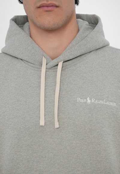 Hanorac gri cu o textură moale, având un logo alb Polo Ralph Lauren pe partea stângă a pieptului și șnururi bej.
