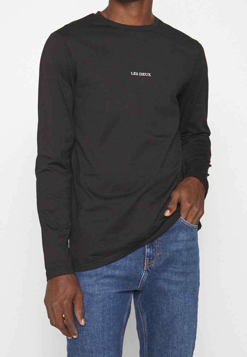 Langärmliges schwarzes T-Shirt aus Baumwolle mit Rundhalsausschnitt und weißem "LES DEUX"-Logo auf der Brust. Glatte Textur mit taillierter Passform.