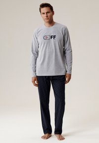 Szary longsleeve z logo "OFF", w połączeniu z granatowymi spodniami od piżamy z małym powtarzającym się wzorem. Miękki materiał, luźny krój.
