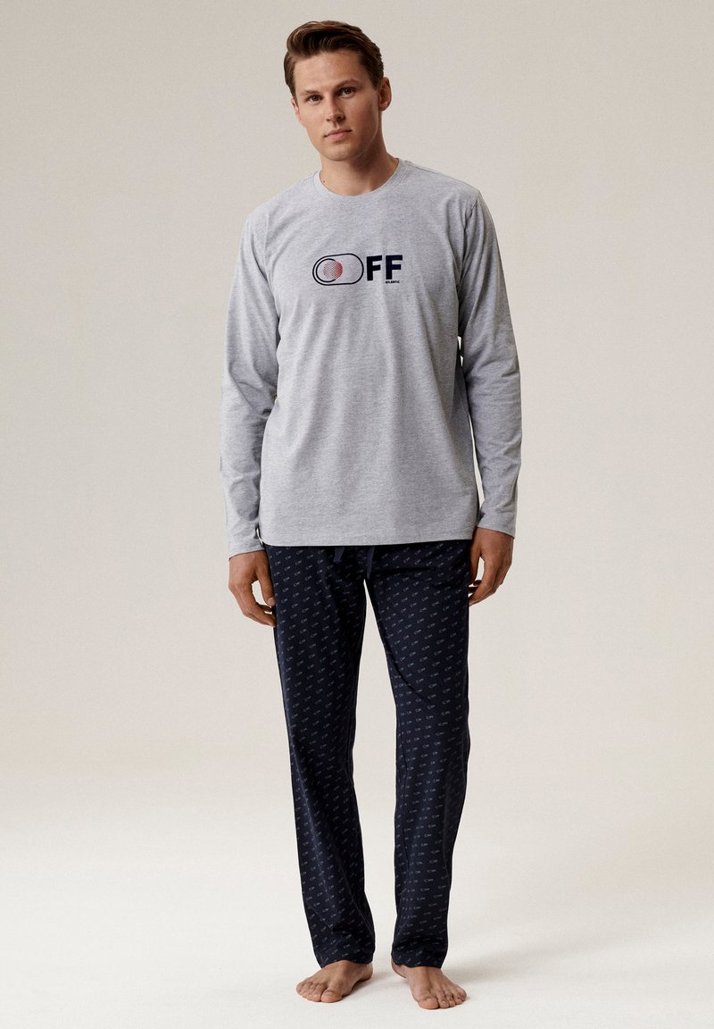 Szary longsleeve z logo "OFF", w połączeniu z granatowymi spodniami od piżamy z małym powtarzającym się wzorem. Miękki materiał, luźny krój.