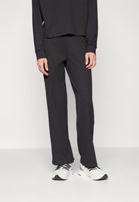 Black ribbed long-sleeve top paired with matching loose-fitting pants. Worn with white athletic shoes featuring black accents.