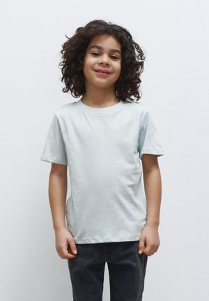Lys grøn bomulds t-shirt med korte ærmer, rund hals og en afslappet pasform, parret med mørkegrå bukser. Simpel design og glat tekstur.