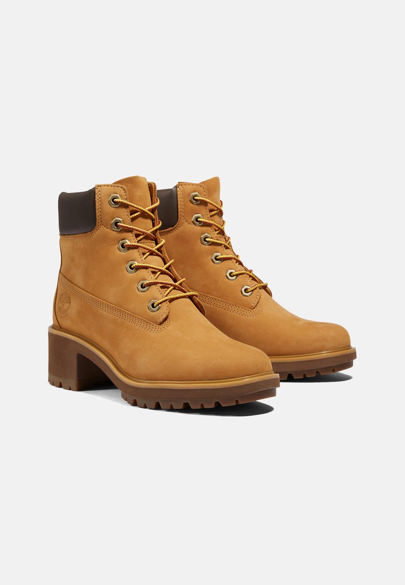 Bottines en cuir tan avec une finition texturée, bout rond, devant à lacets et talon marron, arborant un logo sur le côté.