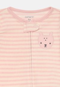 Ensemble pour bébé rayé rose et crème en tissu doux, avec une appliqué de visage d'ours et une fermeture à pression au niveau du cou pour un habillage facile.