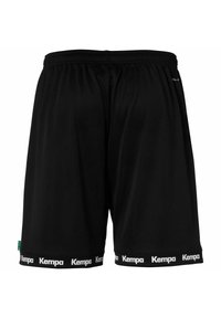 Zwarte sportshorts van lichtgewicht materiaal, met een elastische tailleband en een wit "Kempa" logo op de zoom. Eenvoudig ontwerp, geen patronen.
