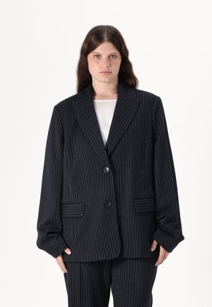 Navy pinstripe blazer med store utskårne lapeler, to frontlommer og en enkelt knappelukking. Laget av strukturert stoff med en glatt tekstur.
