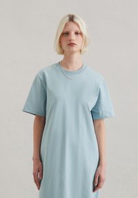 Jasno-niebieska sukienka T-shirt z bawełny, z krótkimi rękawami, okrągłym dekoltem i luźnym krojem, charakteryzująca się gładką fakturą i brakiem widocznych wzorów.