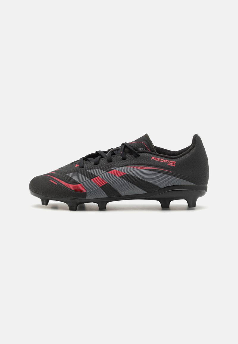 Botas de fútbol negras con acentos en rojo y gris, que cuentan con una parte superior texturizada, cierre de cordones y múltiples tacos moldeados en la suela.