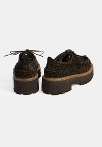 Braune Wildleder-Plateauschuhe mit einem Leopardenmuster, runder Spitze und Schnürdetail. Dicke, strukturierte Gummisohlen mit Profil.