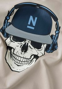T-shirt grafica con uno scheletro in bianco e nero che indossa un cappellino blu e delle cuffie, su uno sfondo beige.
