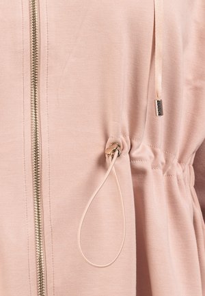 Giacca zip frontale rosa chiaro con vita regolabile, zip metallica e texture in tessuto morbido con dettagli arricciati.