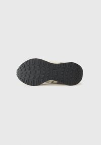 Black rubber outsole with textured grip pattern. Beige and grey upper with minimal accents and a sleek design. Sturdy and functional.