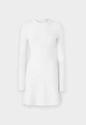 Vestido blanco de canalé con mangas largas, cuello redondo, silueta ajustada y dobladillo acampanado que presenta patrones de canalé verticales y diagonales.