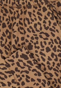 Bruine stof met een onregelmatig leervlekkenpatroon in donkerbruin, zichtbare elastische tailleband en stiksels van zijzakken.