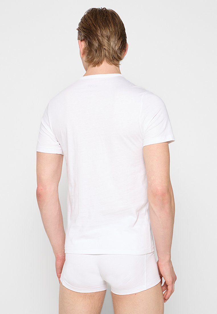 Biała koszulka z krótkim rękawem wykonana z gładkiego, lekkiego materiału, w połączeniu z białymi szortami. Prosty design, brak widocznych wzorów lub akcentów.