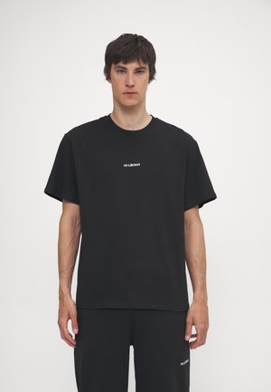 Tricou din bumbac negru cu mâneci scurte, având un mic logo alb în centru. Materialul are o textură netedă și o croială lejeră.