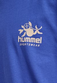 Koninklijk blauwe katoenen t-shirt met een wit "hummel" logo in een gestileerd ontwerp en het woord "SPORTKLEDING" eronder.