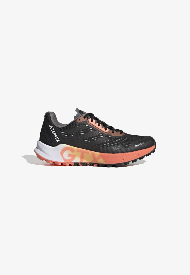 Chaussure de course noire avec tige en Gore-Tex, accents roses, semelle extérieure texturée et branding distinctif. Conception légère pour des performances en plein air.