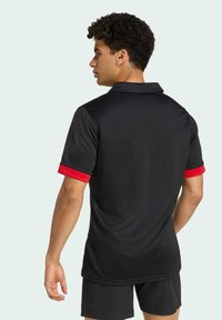 Sort poloshirt med røde detaljer på ærmerne, lavet af glat, åndbart stof; har en krave-design og en afslappet pasform.