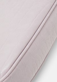 Jasnofioletowa sztuczna skóra o fakturze przypominającej skórę krokodyla z gładkimi krawędziami. Powierzchnia wydaje się miękka i lekko błyszcząca.