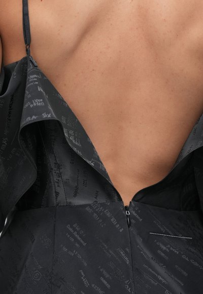 Vestito nero con scollatura bassa sulla schiena, caratterizzato da un collo a balze a strati e una cerniera nascosta sul lato. Il tessuto presenta un motivo grafico.