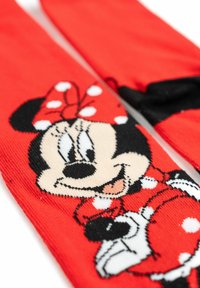 Calzini di cotone rossi con un grafico di un personaggio con un fiocco a pois, volto sorridente e accenti neri. Texture morbida.