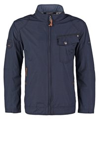 Navyblauwe jas met hoge kraag, ritssluiting aan de voorkant en een borstzak aan de linkerkant. Kenmerkt zich door een textuurafwerking en contrasterende accenten.