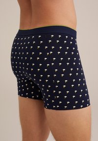 Marina boxershorts i mjukt tyg med ett upprepat mönster av moln och blixtar, med en kontrasterande grön midjeband.