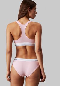 Lichtroze katoenen bh en slipset, met een racerback ontwerp, een witte elastische tailleband met merknaam en een gladde textuur.