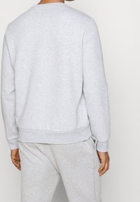 Sudadera de algodón gris con cuello redondo, puños y dobladillo acanalados; combinada con pantalones a juego; diseño simple y sin adornos.