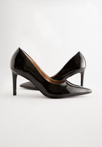 Décolleté nere lucide in vernice con punta a punta e tacco stiletto sottile, caratterizzate da una texture liscia e un design minimalista.