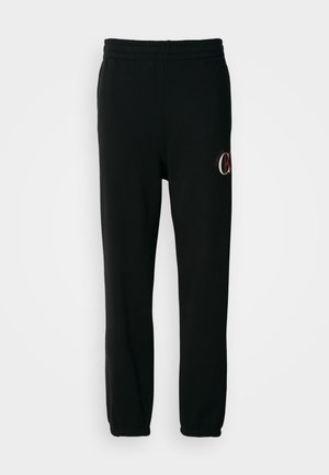 Čierne tepláky z mäkkej bavlnenej zmesi, s elastickým pásom a manžetami. Obsahujú malý logo akcent na stehne.