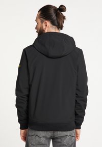 Jachetă neagră cu glugă, cu un finisaj neted, manșete și tiv ribbate, și detaliu cu logo pe umărul stâng. Vedere din spate care arată un design minimalist.