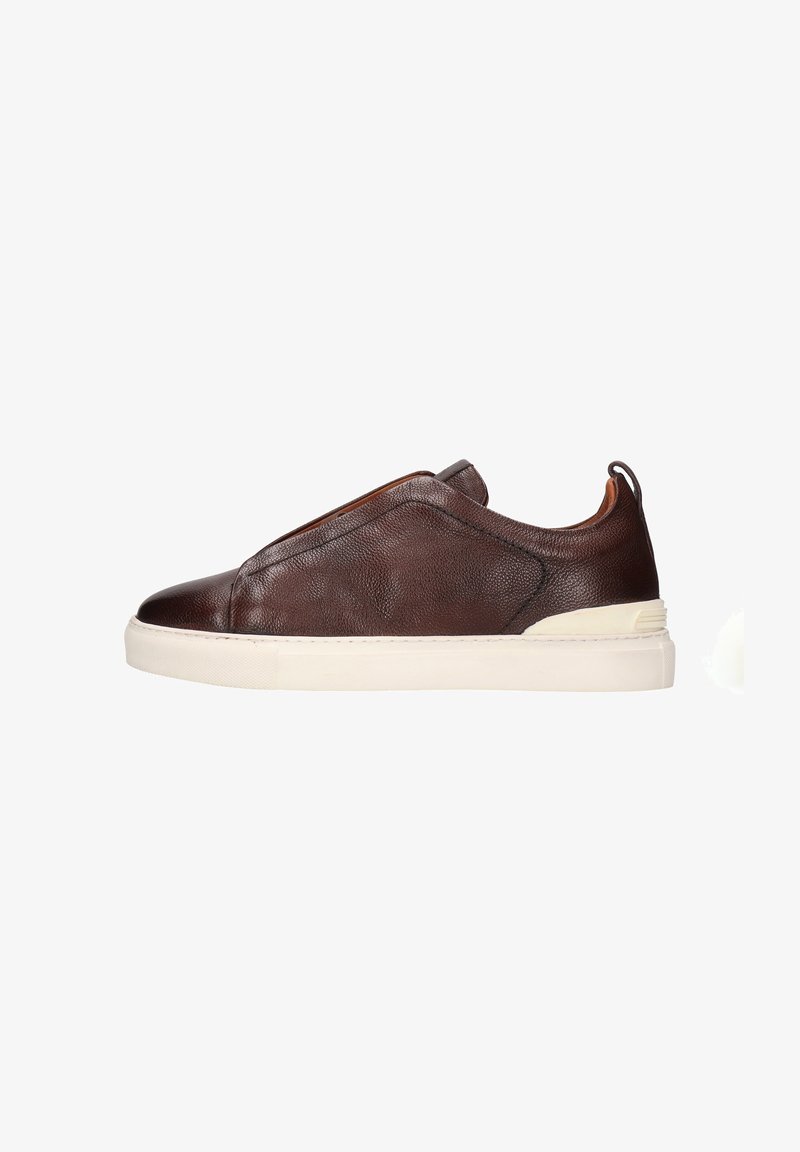 Zapatilla slip-on de cuero marrón con una textura suave, presenta un cuello acolchado y una suela de goma blanca contrastante.