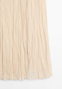 Beige plisseret stof med lodrette folder og en let tekstureret overflade, vist mod en hvid baggrund.