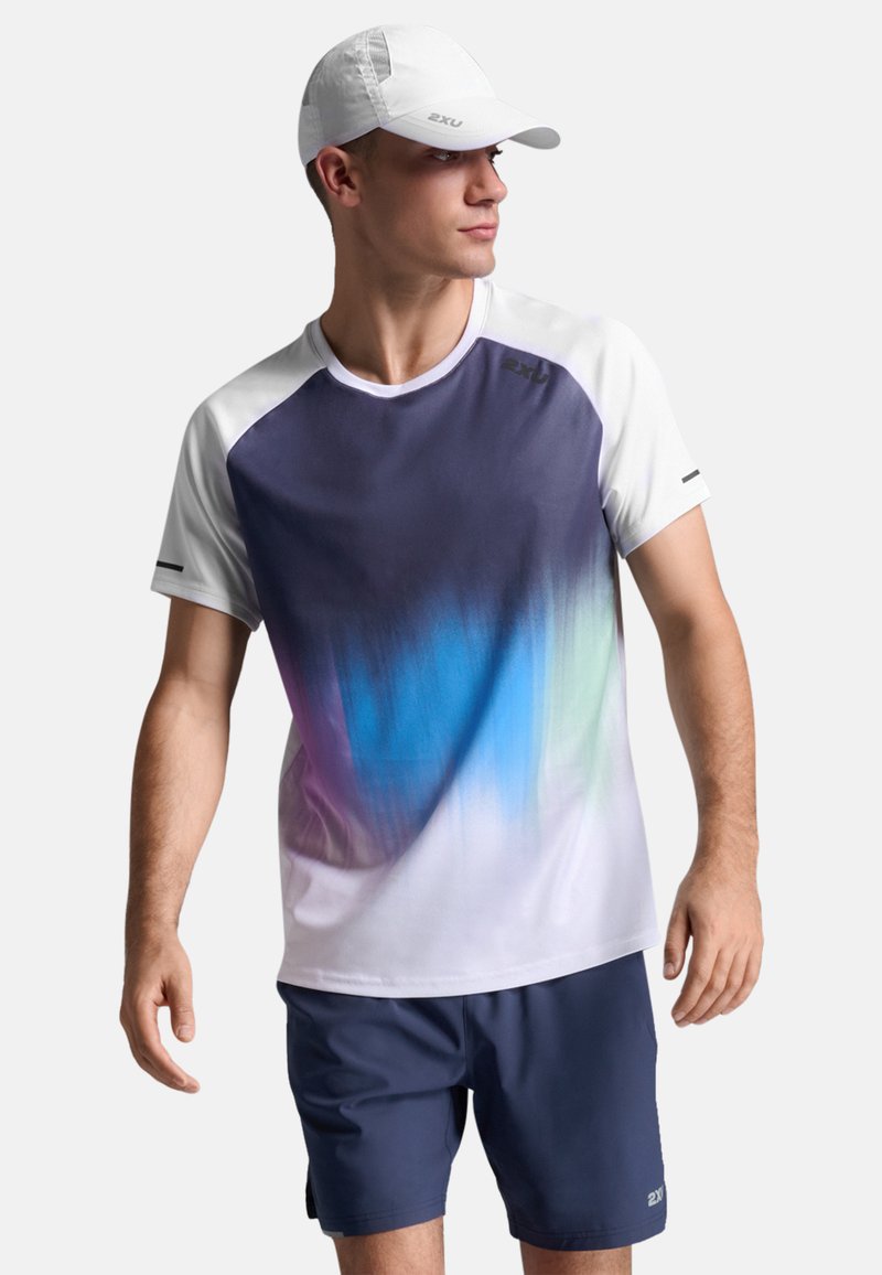 Conjunto deportivo masculino que incluye una camiseta de manga corta de secado rápido con un degradado de azul a blanco y pantalones cortos azul marino. Una gorra blanca completa el atuendo.