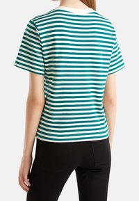 Randig t-shirt med gröna och vita horisontella ränder, korta ärmar, rund halsringning och en mjuk bomullstextur.