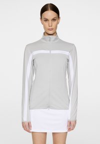 Hellgraue Zip-Jacke mit weißen Seitenpaneelen, aus glattem Stoff; verfügt über einen Stehkragen und Branding auf der Brust.