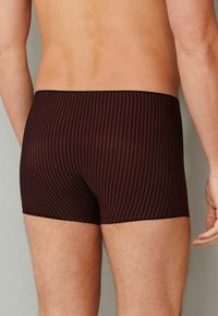 Black and dark red striped boxer briefs with a snug fit, featuring an elastic waistband and smooth texture.