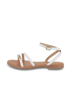 Sandales plates blanches en cuir avec trois fines lanières, boucle de cheville ajustable et semelle intérieure beige. Détails de couture remarquables le long de la semelle.