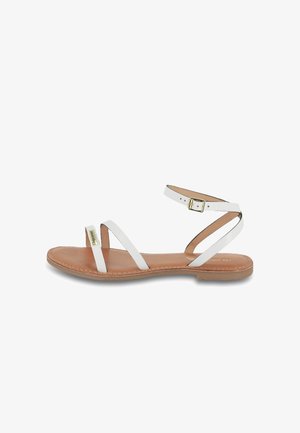 Sandales plates blanches en cuir avec trois fines lanières, boucle de cheville ajustable et semelle intérieure beige. Détails de couture remarquables le long de la semelle.