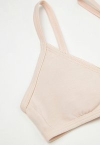 Bralette en tissu rose doux avec des bretelles fines, un design sans coutures et des détails froncés à la base. Texture lisse, style minimaliste.