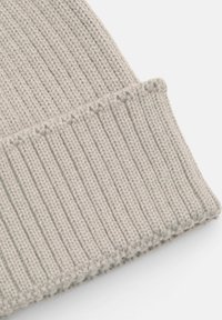 Világosszürke kötött gyapjú sapka, hajtott bordás szegéllyel, fehér háttérrel.