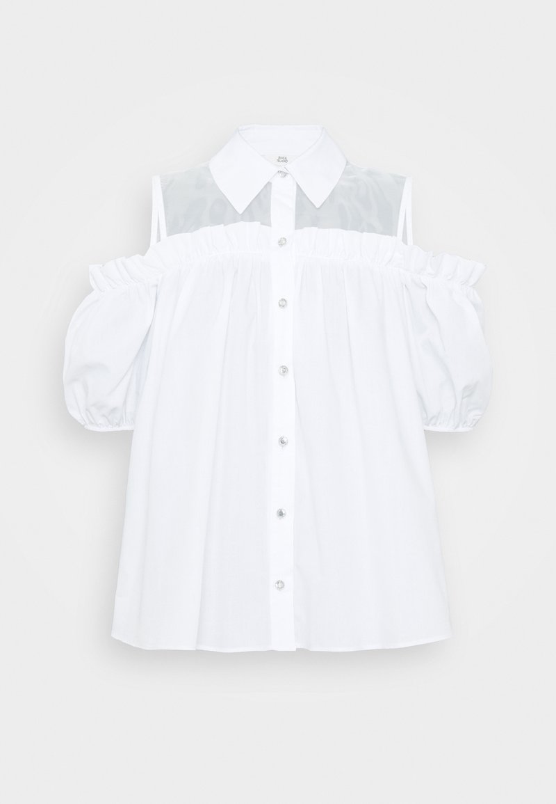 Chemise blanche décolletée avec un col, des manches bouffantes, des accents froncés et un tissu transparent au niveau des épaules. Fermeture à boutons sur le devant.