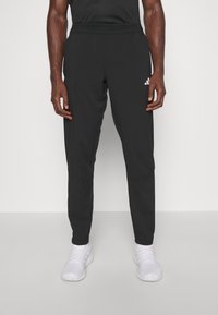 Svarta träningsbyxor med smal passform, med resårmidja och sidofickor. Tillverkade av lätt, slätt material.