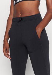 Zwarte joggingsbroek met een elastische tailleband, trekkoord, zijzakken en een gladde, zachte textuur. Geschikt voor casual kleding.