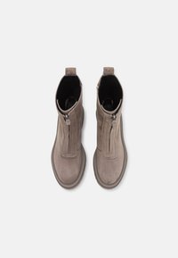 Une paire de bottines en daim taupe, avec des fermetures éclair à l'avant et des languettes, vue de dessus sur un fond blanc.