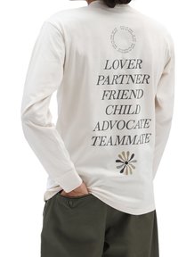 Camisa de manga larga color crema con texto negro en la parte posterior: "AMANTE, COMPAÑERO, AMIGO, NIÑO, DEFENSOR, COMPAÑERO DE EQUIPO" con un diseño floral multicolor.