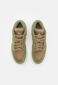 Paire de baskets basses marron et vertes avec lacets et logo Jumpman visible sur la languette beige, vue de dessus sur fond blanc.